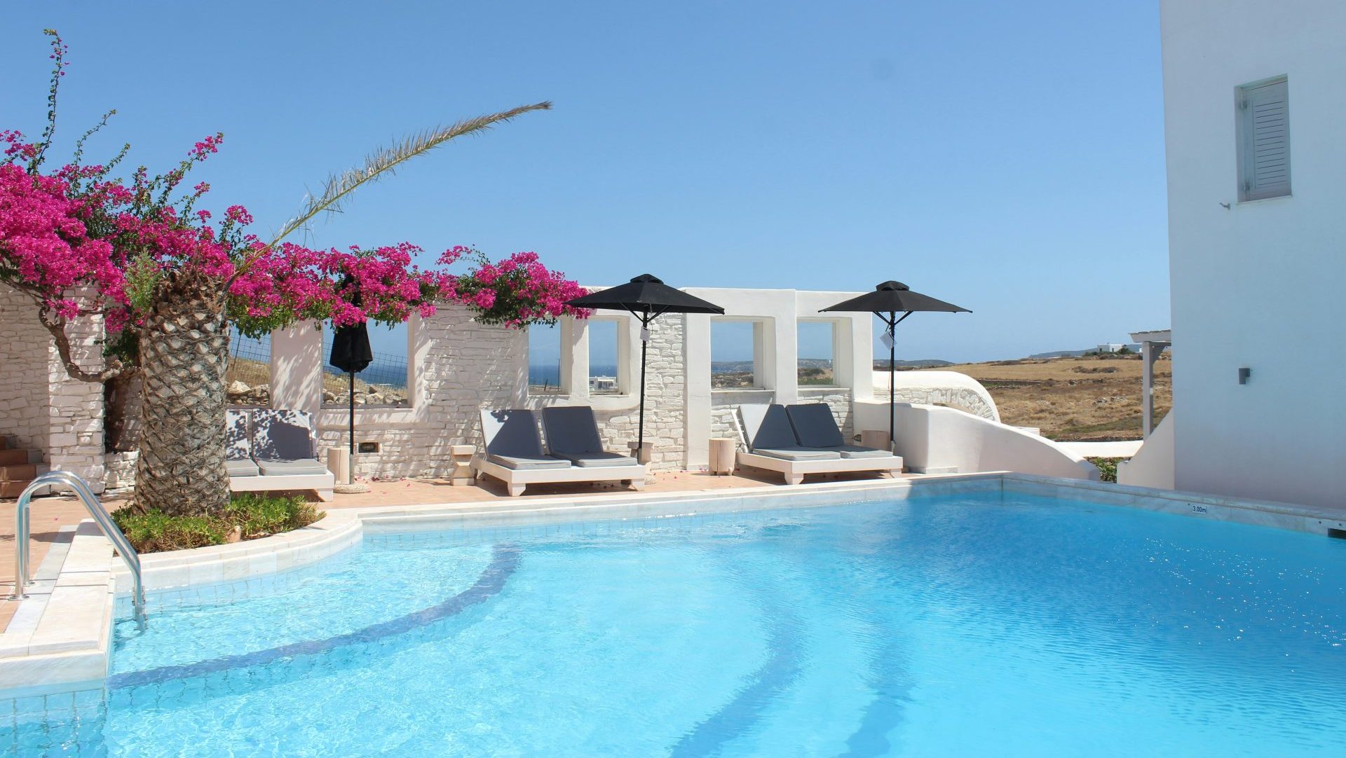 white and brown concrete house near swimming pool under blue sky during daytime